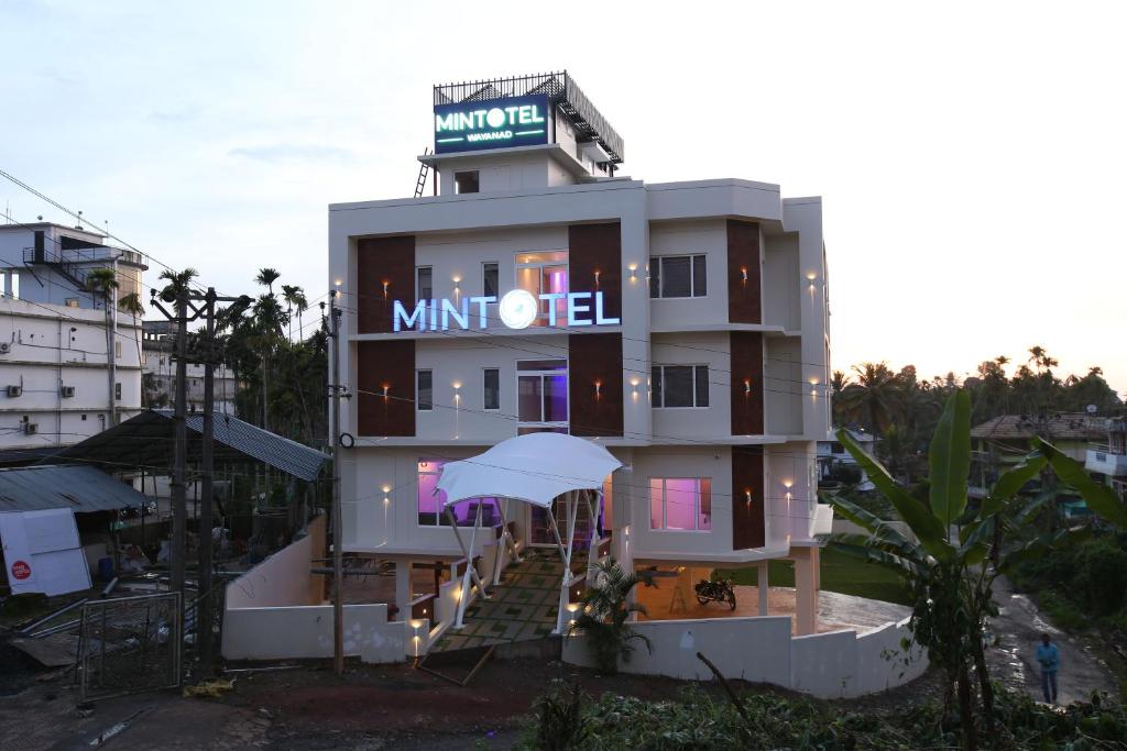 a hotel with an umbrella in front of a building at Mintotel Wayanad in Sultan Bathery