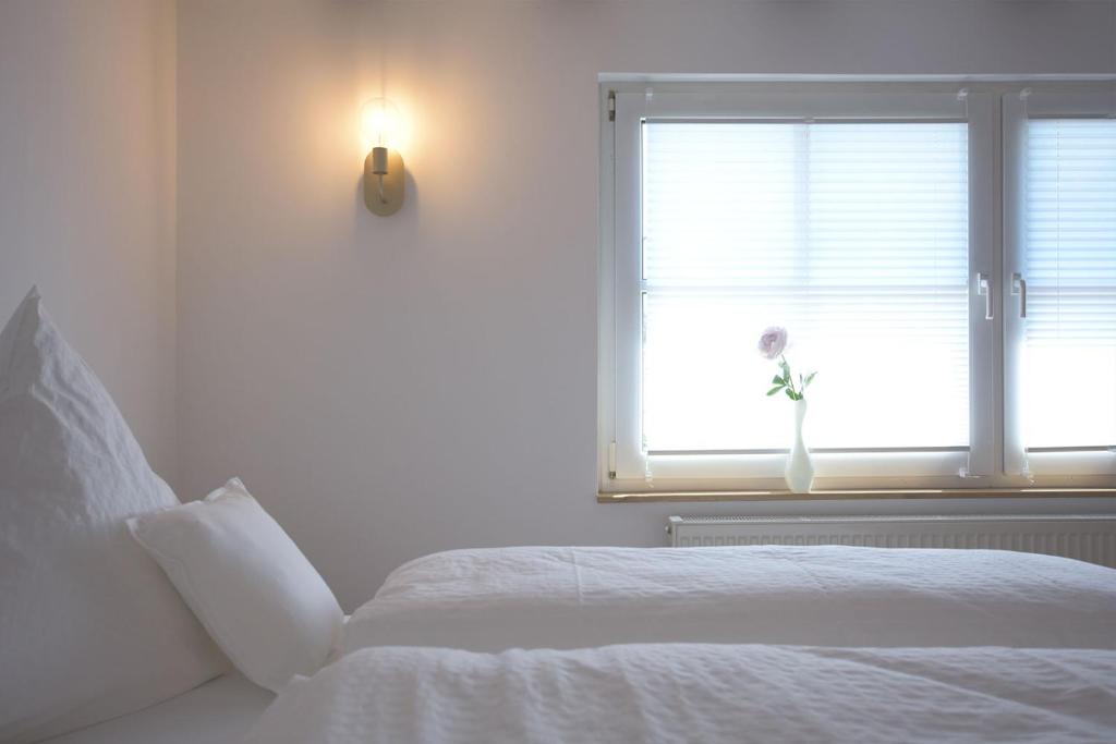 a white bedroom with a bed and a window at Laubach Ferienwohnung - Fam.Lorenz in Laubach