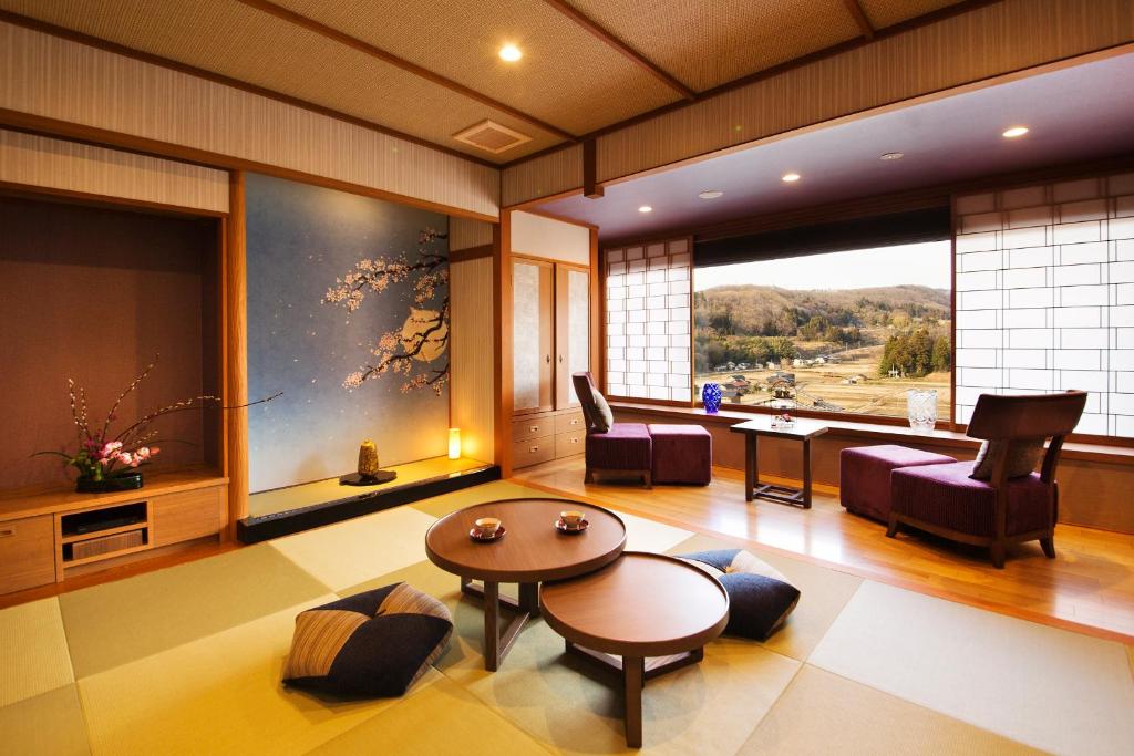 a living room with a table and chairs and a large window at Kanazawa Hyakurakusou in Kanazawa