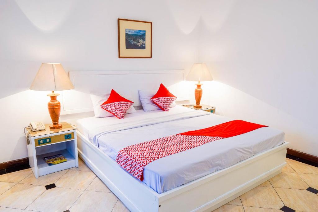 1 dormitorio con 1 cama con almohadas rojas y blancas en Super OYO Collection O 1452 Hotel Utari en Bandung