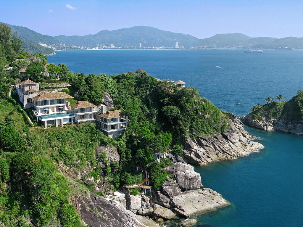 a house on a cliff next to the water at Villa Minh in Kamala Beach