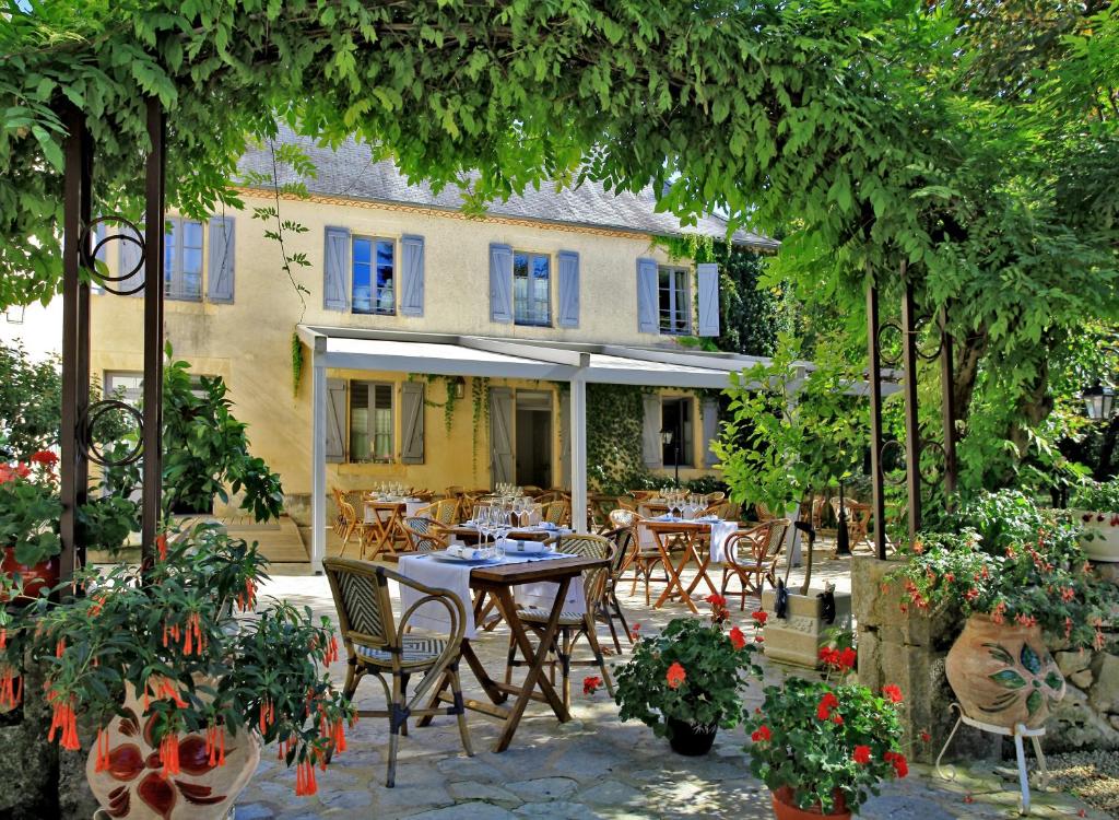 a patio with a table and chairs in front of a building at Le Moulin de Mitou in Auriac-du-Périgord