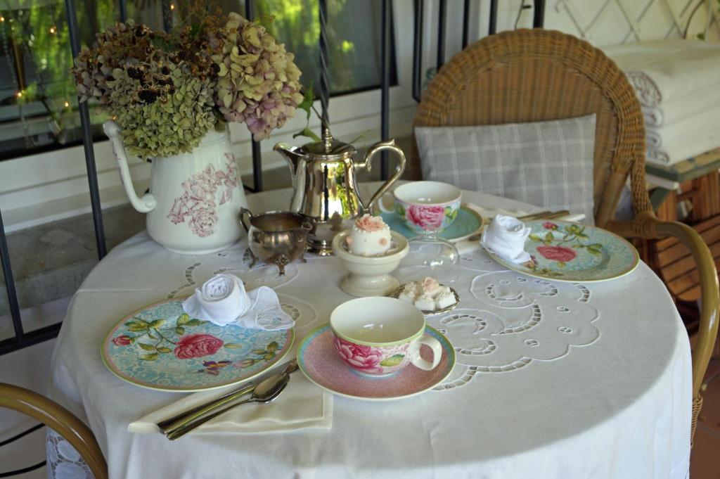 un tavolo con piatti e tazze e un vaso con fiori di Im Röseligarten a Wolfhausen