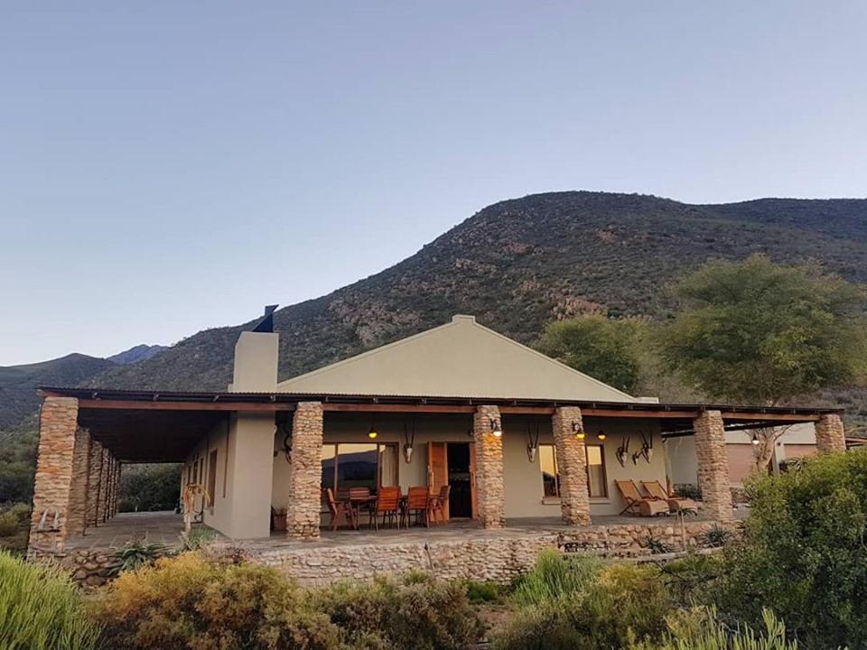 a house with a mountain in the background at Ribboksfontein Guest Farm in De Rust