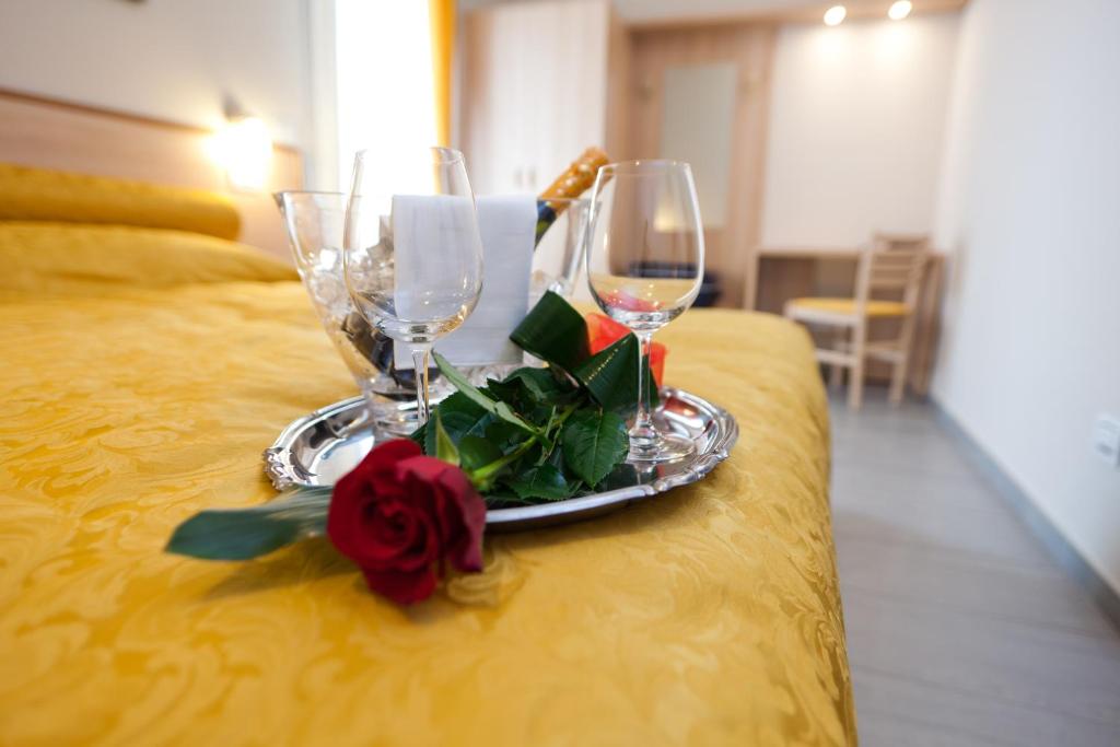 a tray with two wine glasses and a rose on a bed at Motel Karibe in Fratta Polesine