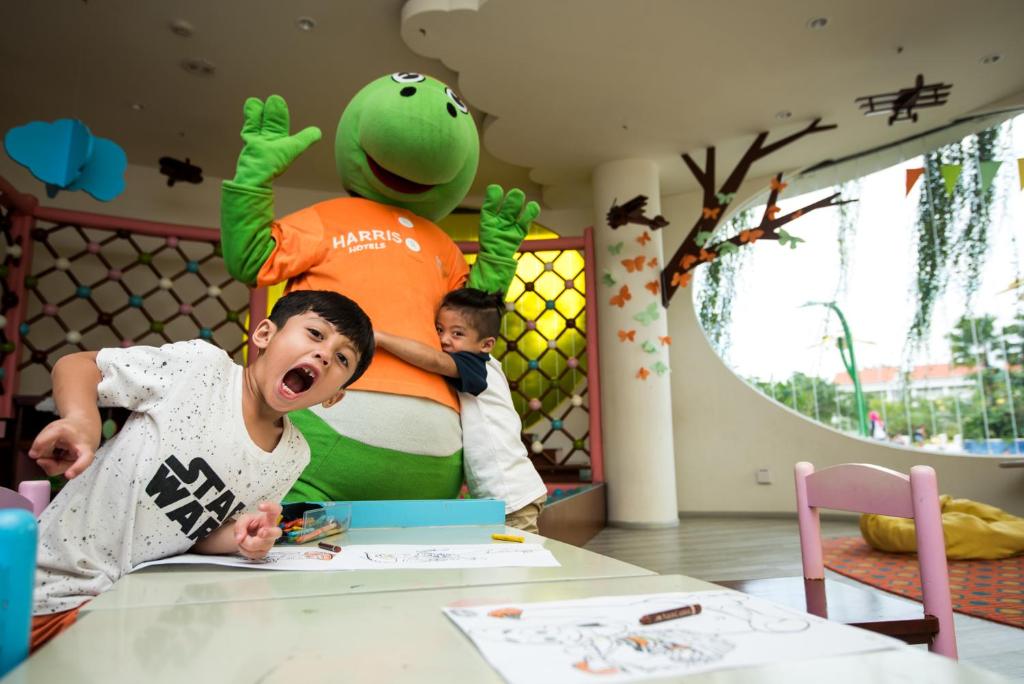 a young boy laying on a table in a room with a stuffed toy at HARRIS Resort Barelang Batam in Sagulung