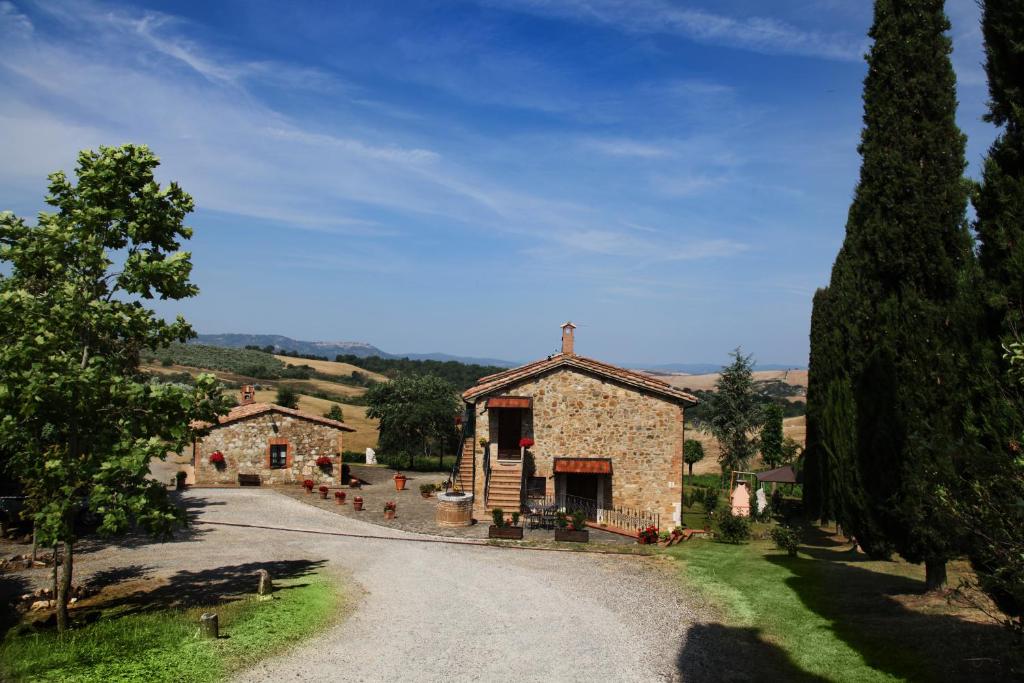 an old stone building on a gravel road at Agriturismo Bagnaia in San Quirico dʼOrcia
