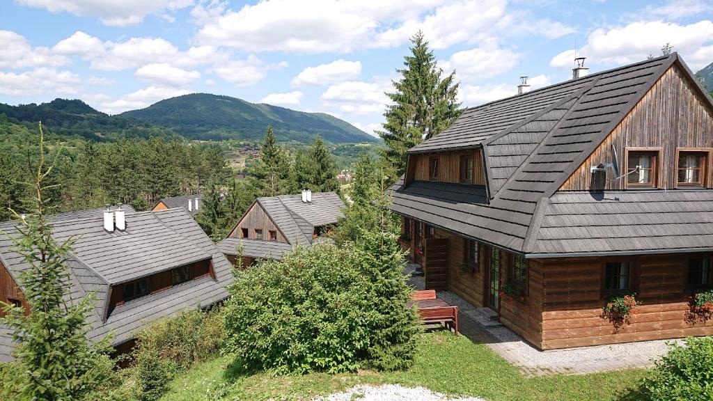 a wooden house in a village with mountains in the background at Drevenice Amálka v Terchové in Terchová