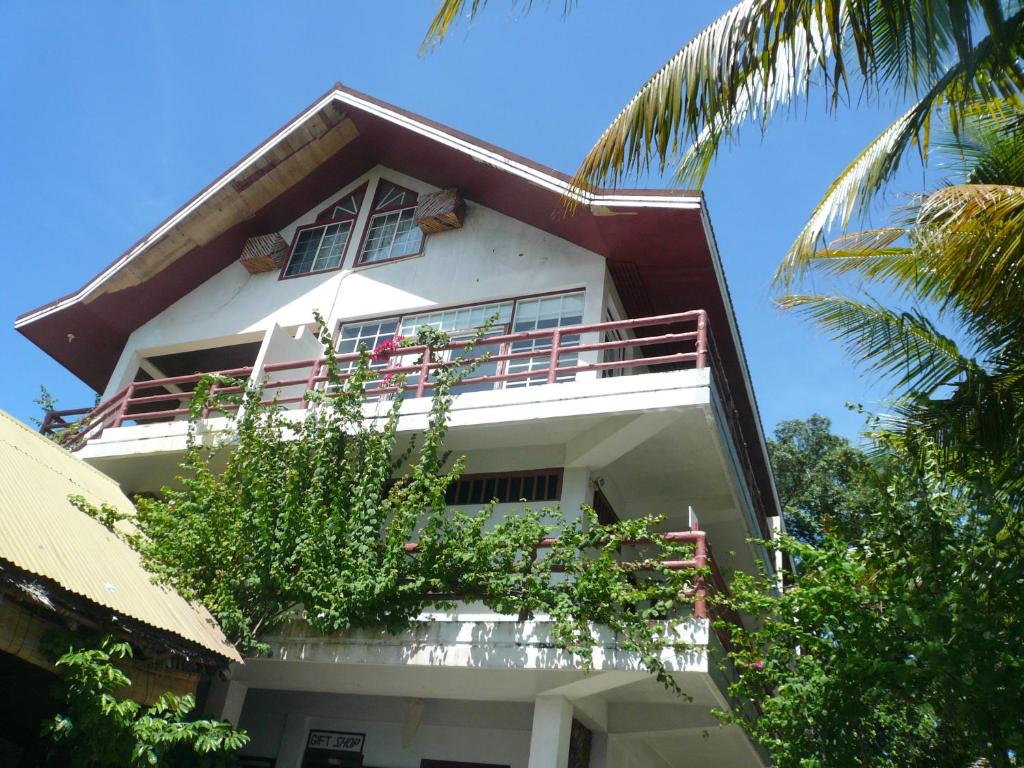ein weißes Gebäude mit einem Balkon und einer Palme in der Unterkunft ANTELOPE GUESTHOUSE in Koror
