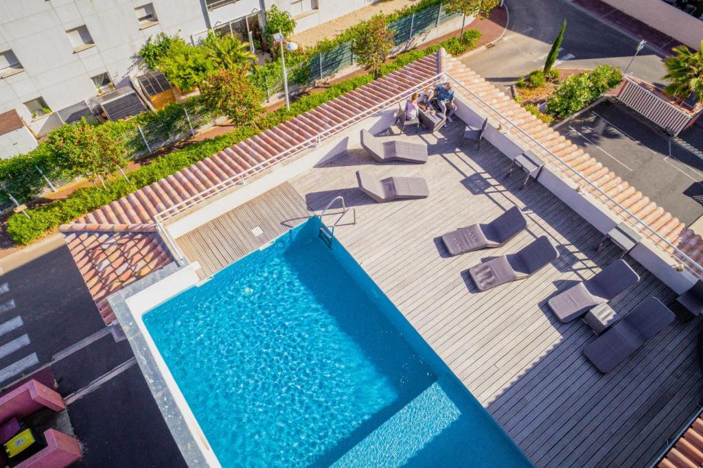 uma vista sobre uma piscina com espreguiçadeiras em Hotel Grand Cap Rooftop Pool em Agde