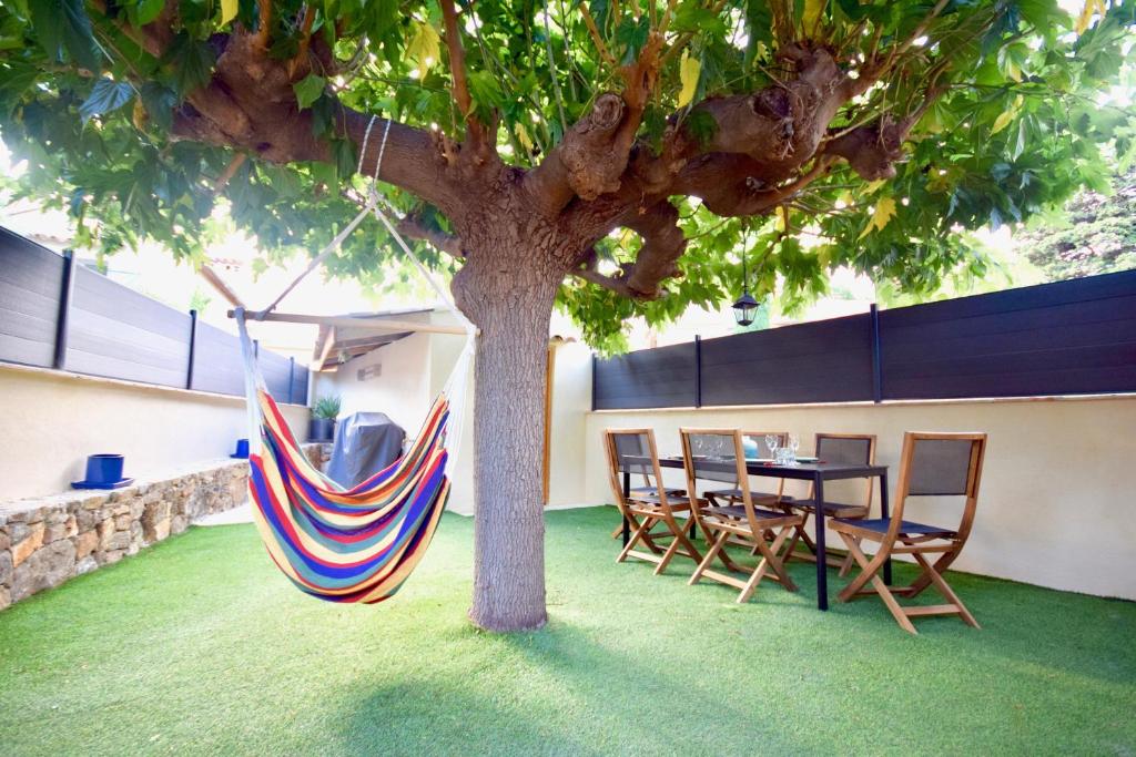 eine Hängematte, die von einem Baum neben einem Tisch und Stühlen hängt in der Unterkunft Charmante maison centre-ville Sainte-Maxime, plages à 2 pas in Sainte-Maxime