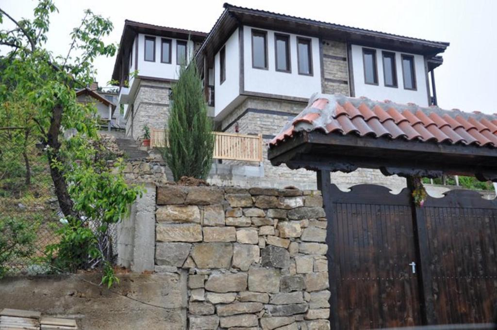 a house with a wooden gate and a stone wall at Panorama Complex in Tvŭrditsa