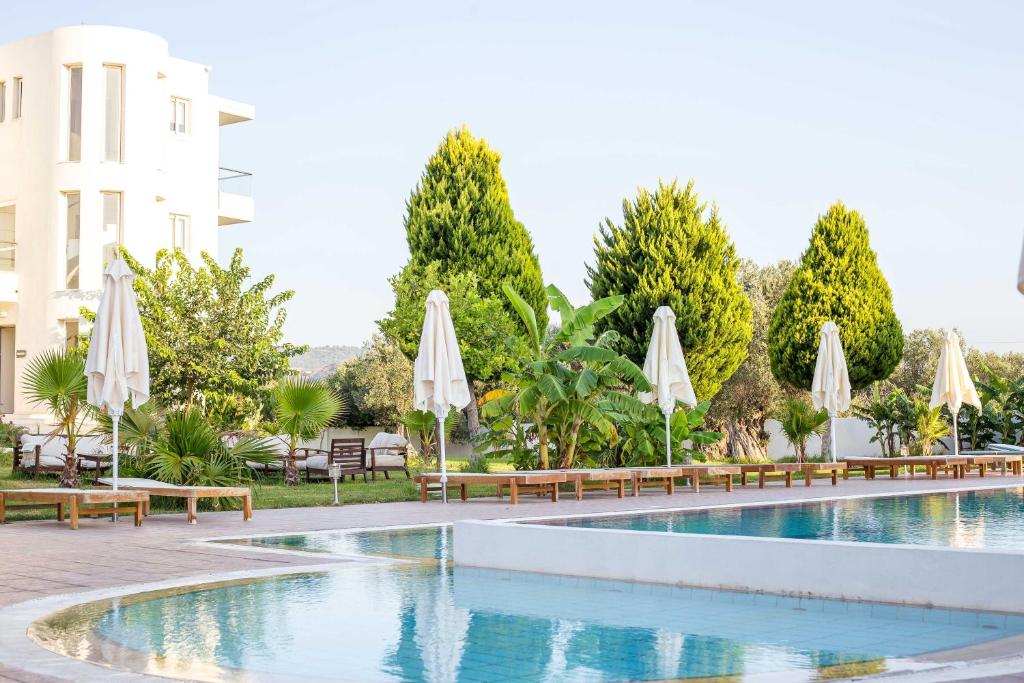 ein Pool in einem Hotel mit Sonnenschirmen und Stühlen in der Unterkunft Evita in Faliraki