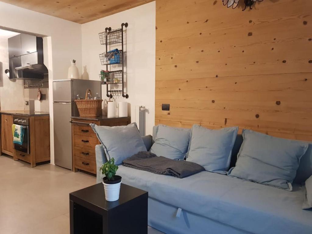 a blue couch in a living room with a wooden wall at Milla Appartamento 4-6 letti - Pontagna -1km Ponte di Legno T04416 in Villa Dalegno