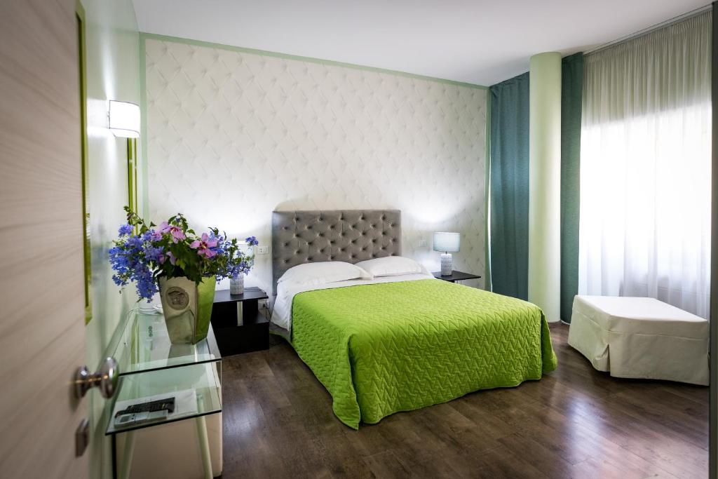 a bedroom with a bed with a green blanket and flowers at B&B Residenza Gregorio VII in Rome