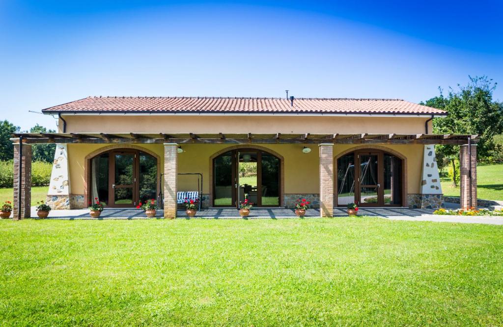a house with a porch and a green lawn at La Dolce Mela in Buonabitacolo