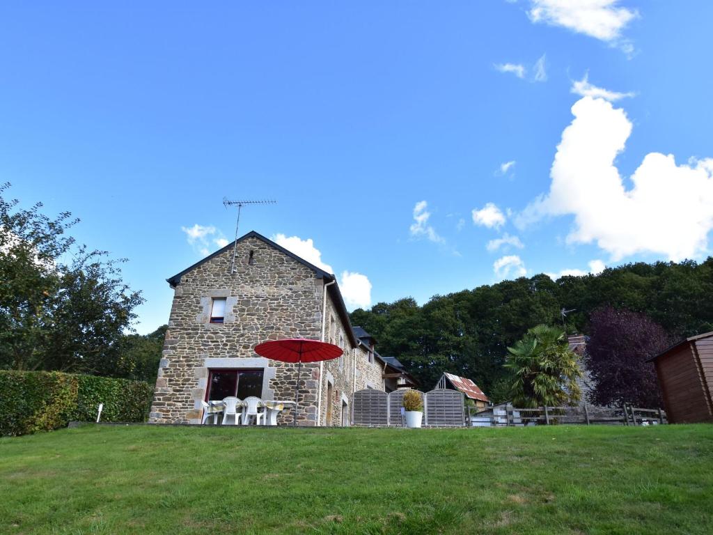 una sombrilla roja frente a una casa de piedra en Cosy chalet with private garden in Normandy, en Isigny-le-Buat