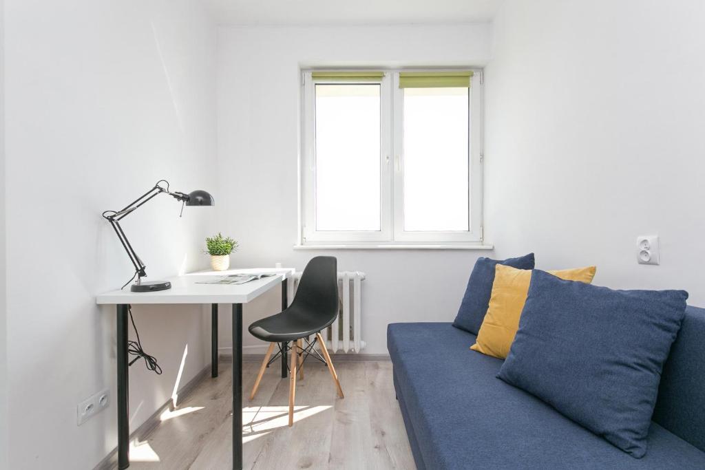 a living room with a blue couch and a desk at Rooms4Less in Gdańsk