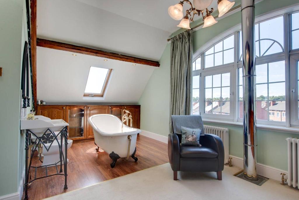 Cette chambre comprend une chaise, un bureau et une fenêtre. dans l'établissement Carnegie Library: Shakespeare Apartment 3 Bedroom, à Mexborough