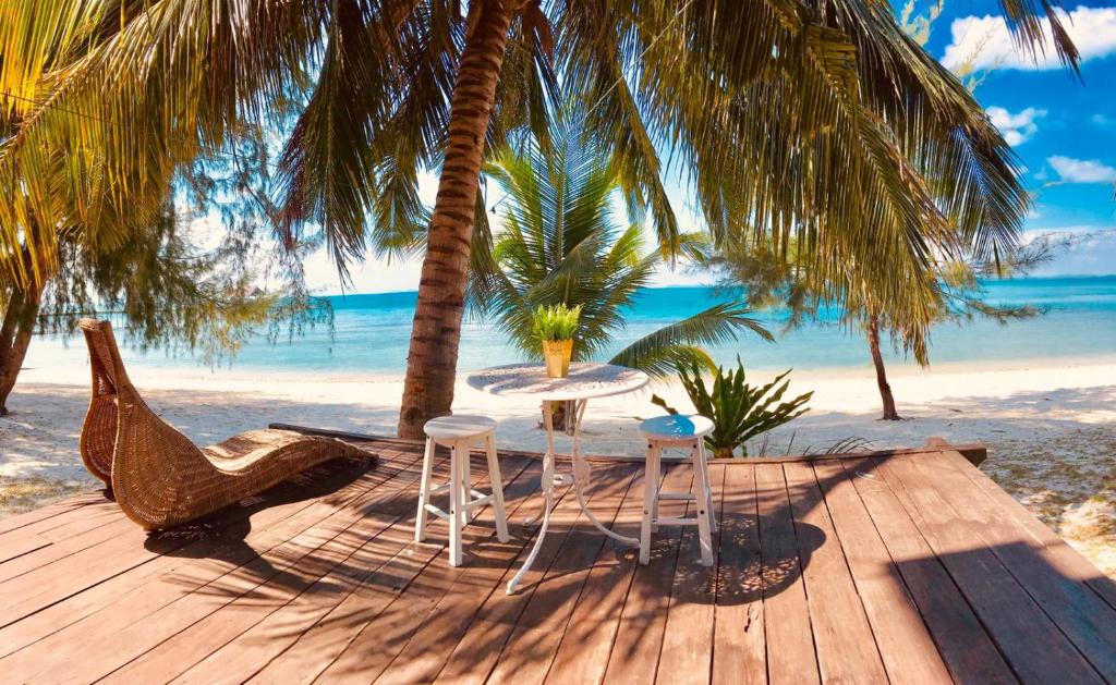- une table et des chaises sur une terrasse en bois sur la plage dans l'établissement Bayu Lestari Island Resort, à Mersing