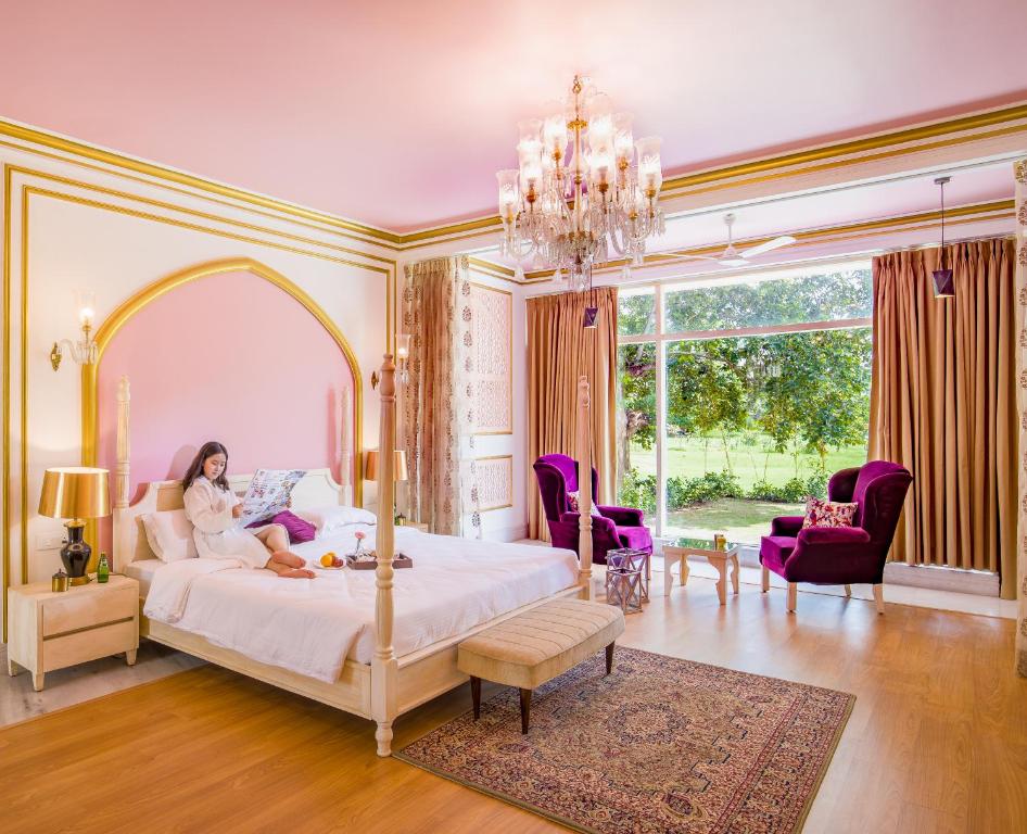 a woman sitting on a bed in a bedroom at Rose Amer in Jaipur