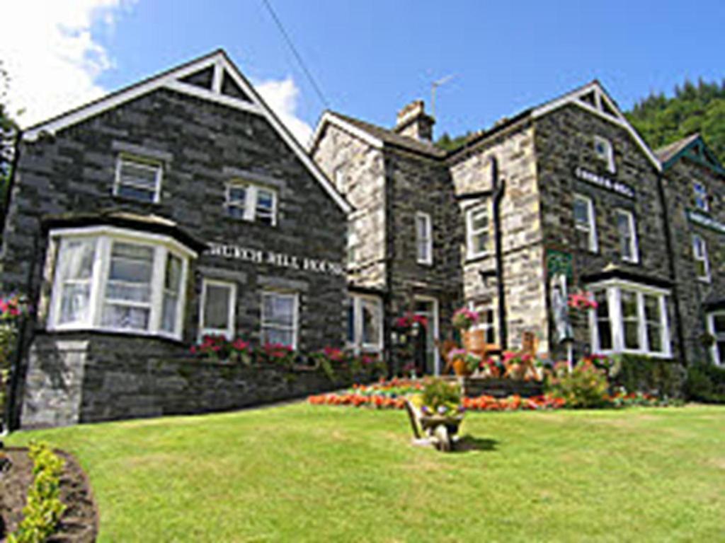 a large stone house with a grass yard at Church Hill House in Betws-y-coed