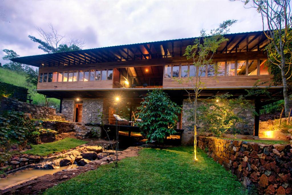 a house with a stone wall and a yard at Sati Villa Kandy Sri Lanka in Kandy