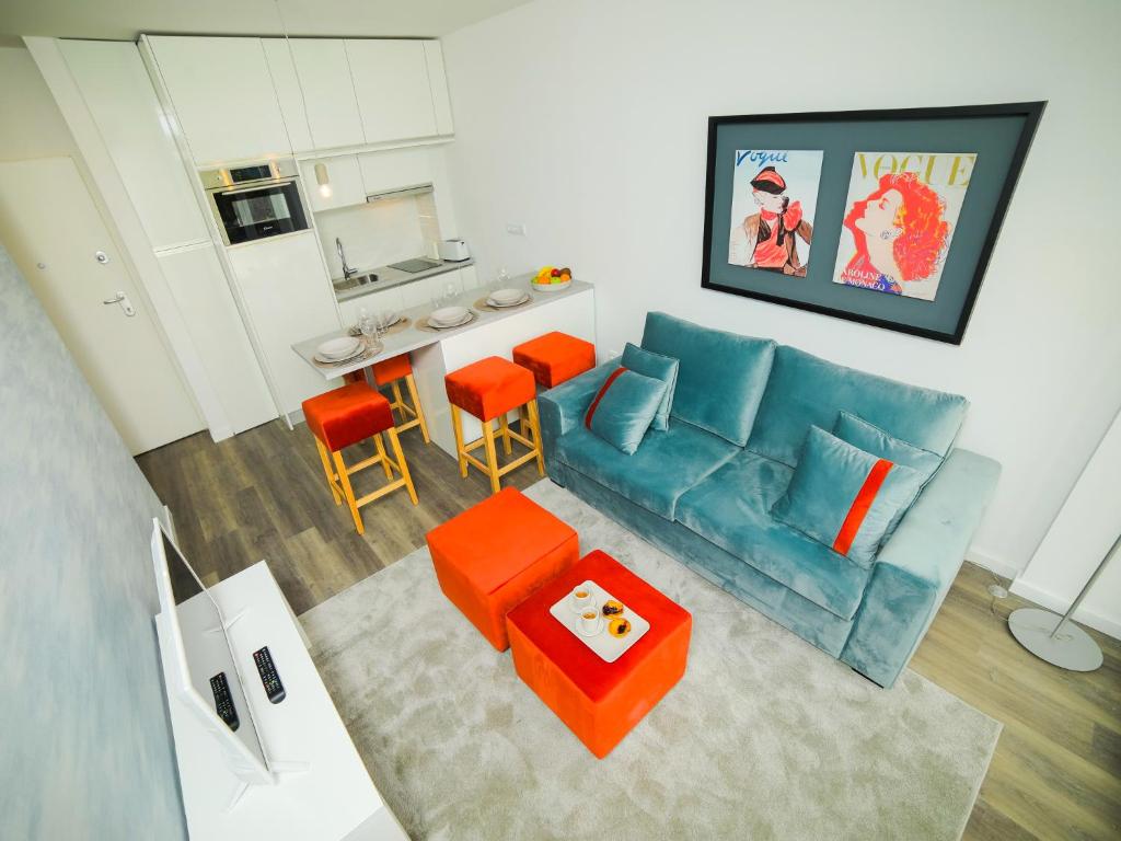 a living room with a blue couch and orange chairs at Angel Flats in Porto