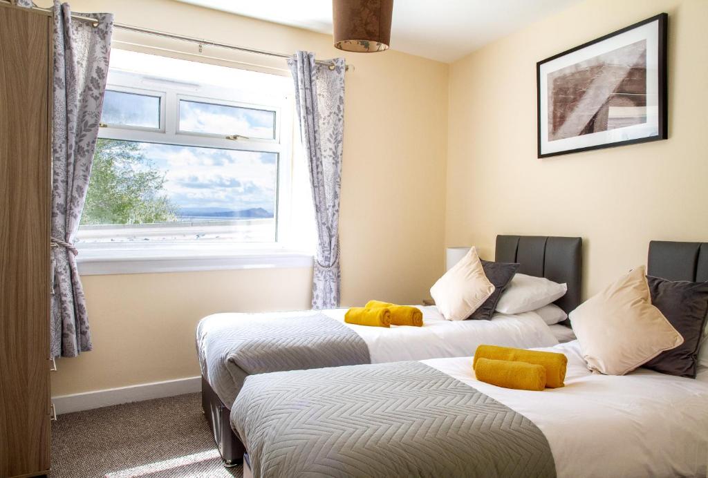 two beds in a room with a window at Carvetii - Borthwick House - Ground floor flat in Kinghorn