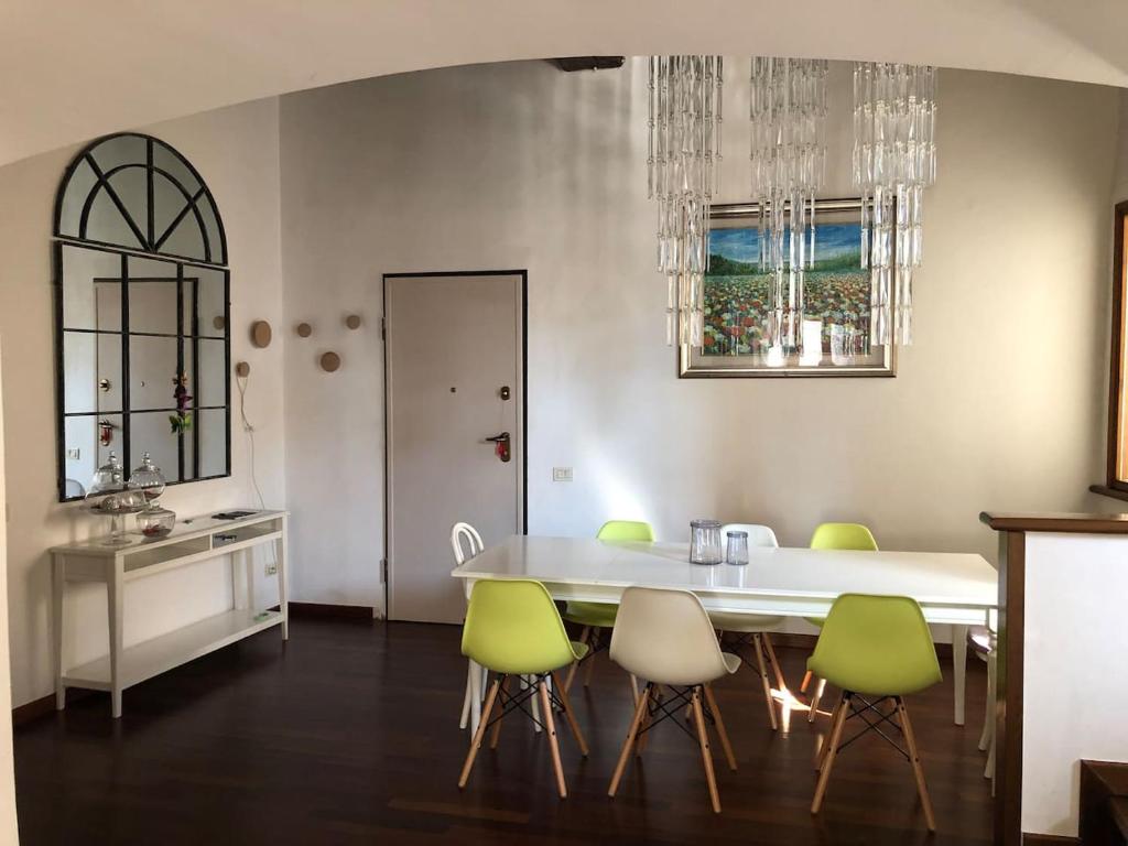 uma sala de jantar com uma mesa branca e cadeiras verdes em Maison Elodie em Narni