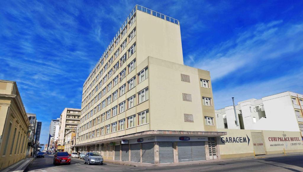 un edificio blanco alto en una calle con coches aparcados delante en Curi Palace Hotel, en Pelotas