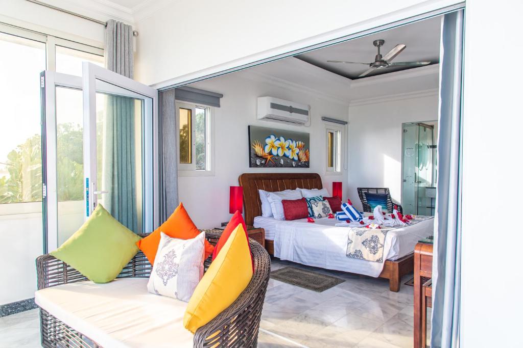 a bedroom with a bed and a couch with colorful pillows at Treasure Island Retreat in Anse Kerlan