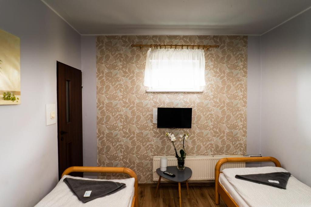 Pokój z dwoma łóżkami i telewizorem na ścianie w obiekcie Zajazd Pod Lipami w mieście Lipno