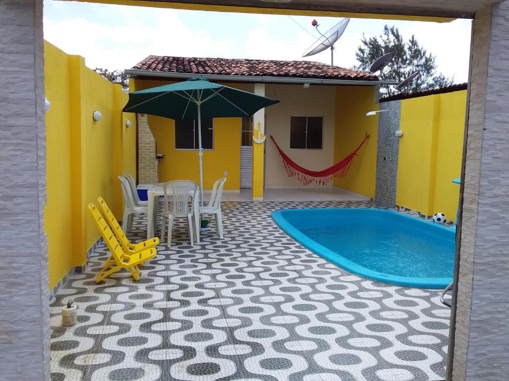 żółty dom z basenem, stołem i parasolem w obiekcie Casa São Miguel dos Milagres w mieście São Miguel dos Milagres