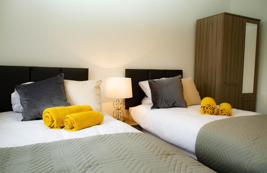 a bedroom with two beds with yellow towels on them at Carvetii - Kings House - 20mins to Edinburgh in Inverkeithing