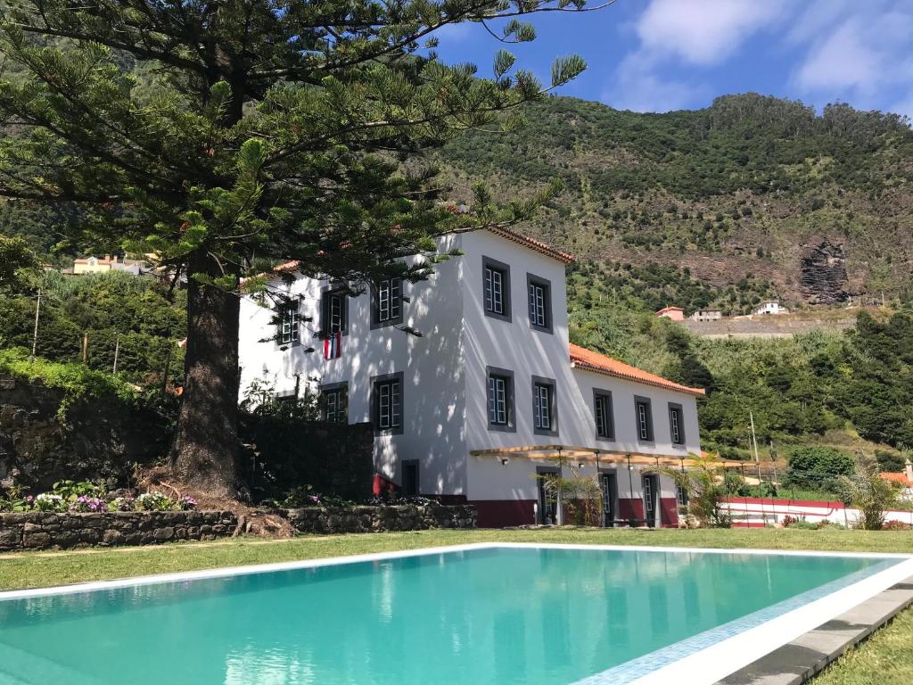 uma casa com piscina em frente a um edifício em Casa Oliveira Esmeraldo - Guest Houses em São Vicente