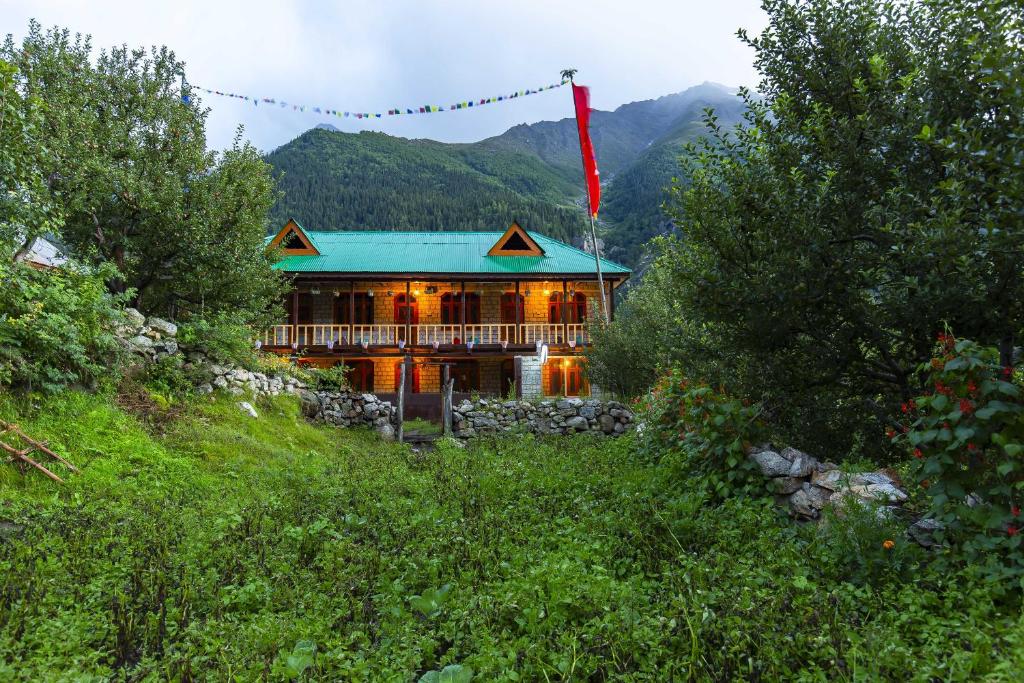 a large house with a green roof in the mountains at Zostel Homes Rakchham (Kinnaur/Sangla/Chitkul) in Saturang