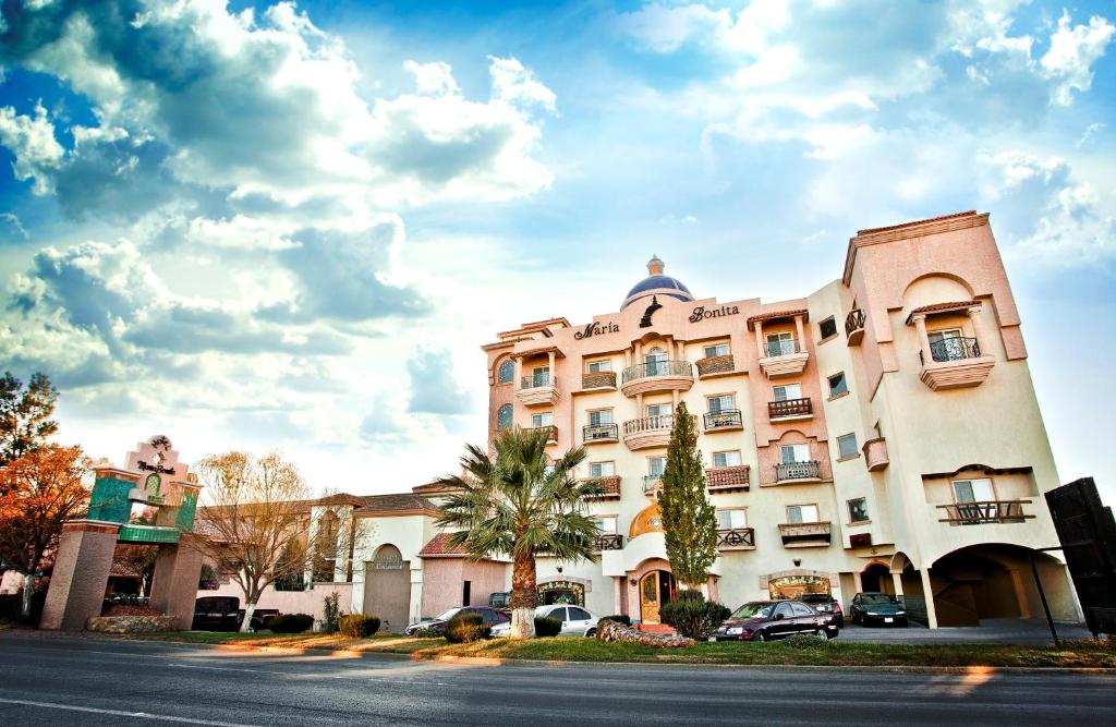 ein Gebäude mit Autos, die vor einer Straße geparkt sind in der Unterkunft Business Hotel & Suites María Bonita in Ciudad Juárez