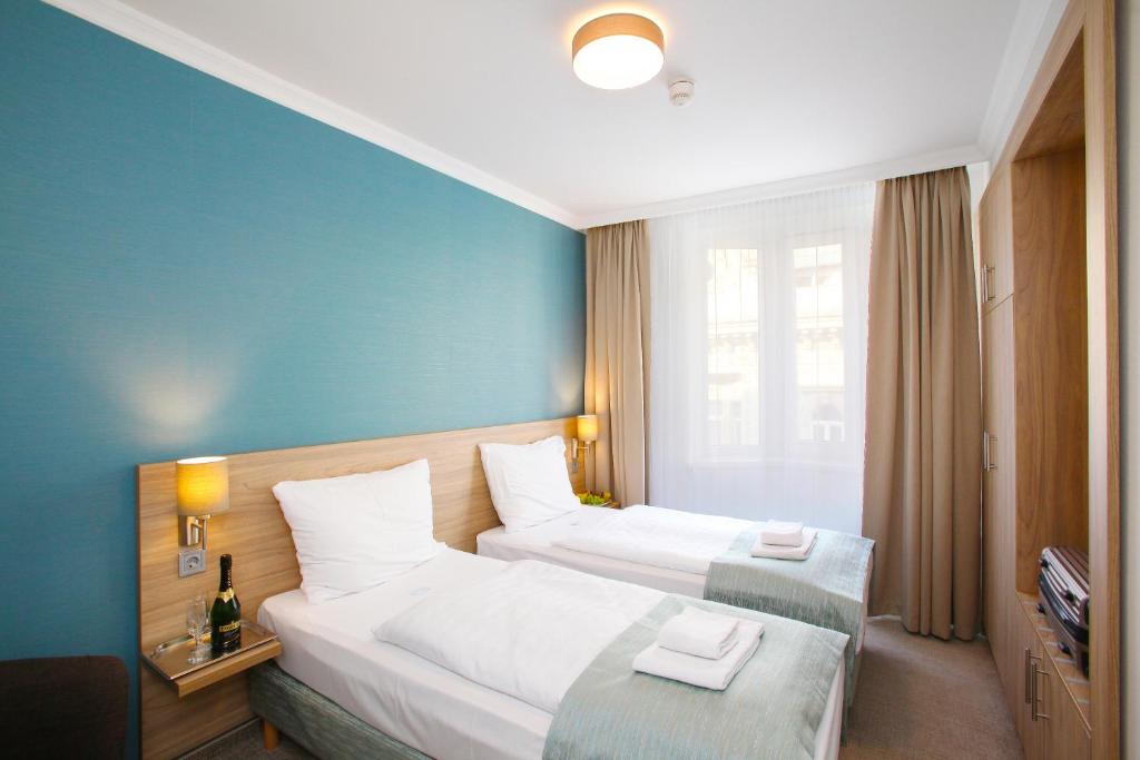 two beds in a hotel room with blue walls at Medos Hotel in Budapest