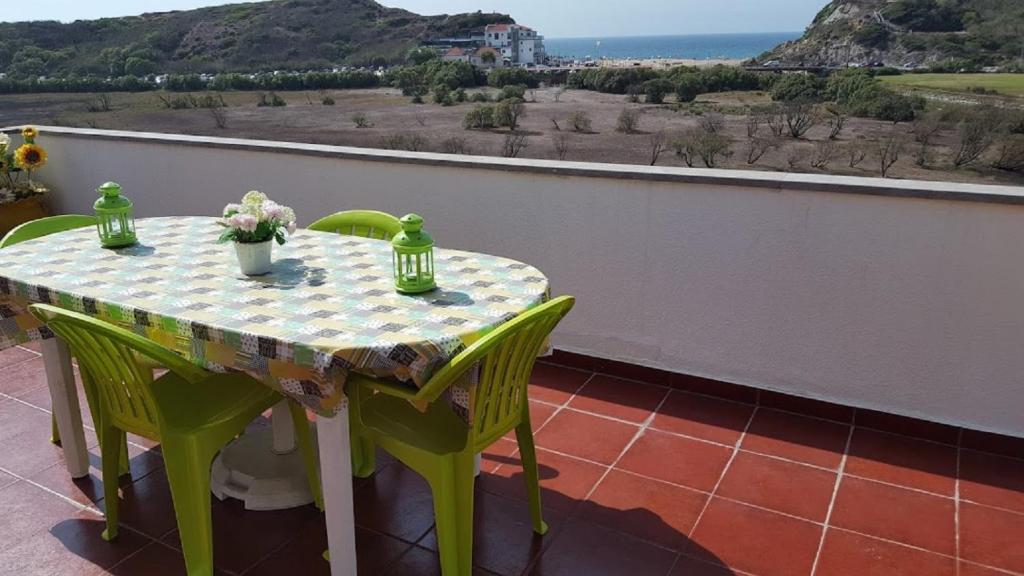 a table and chairs on a balcony with a view of the ocean at Entre o Mar e a Serra in Maceira