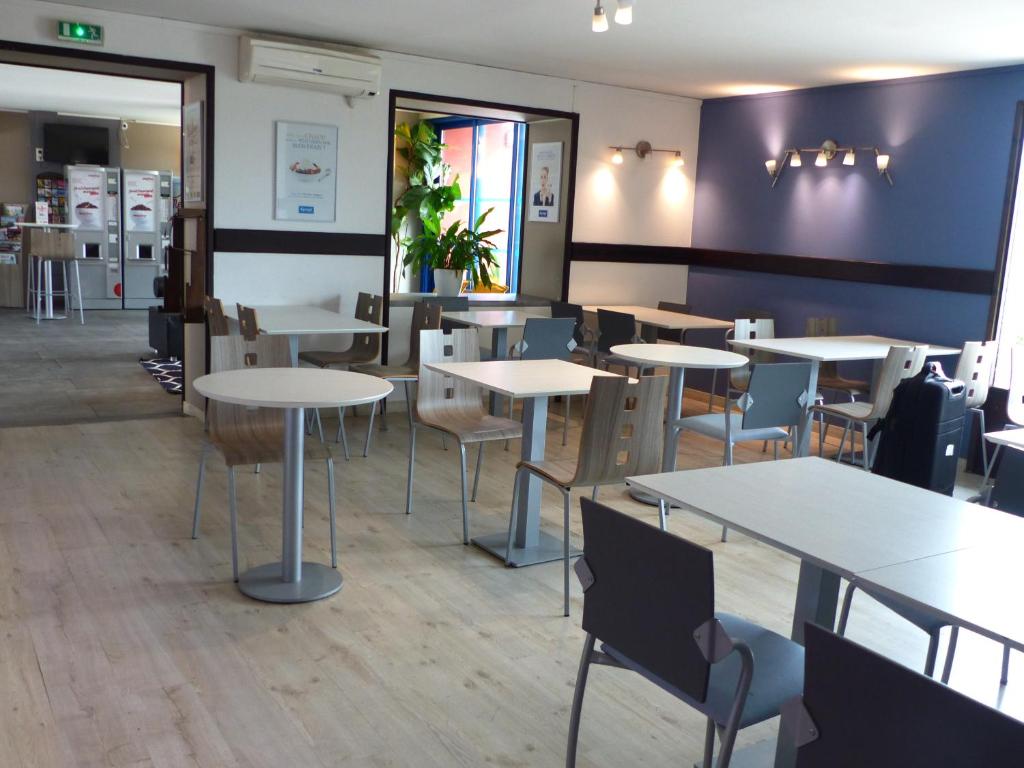 a dining room with tables and chairs in a restaurant at Kyriad Toulouse Sud - Roques in Roques Sur Garonne