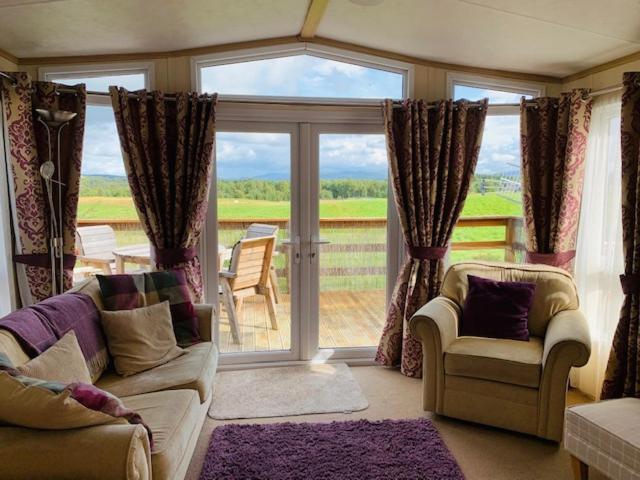 a living room with a couch and chairs and a large window at Invernevis in Boat of Garten