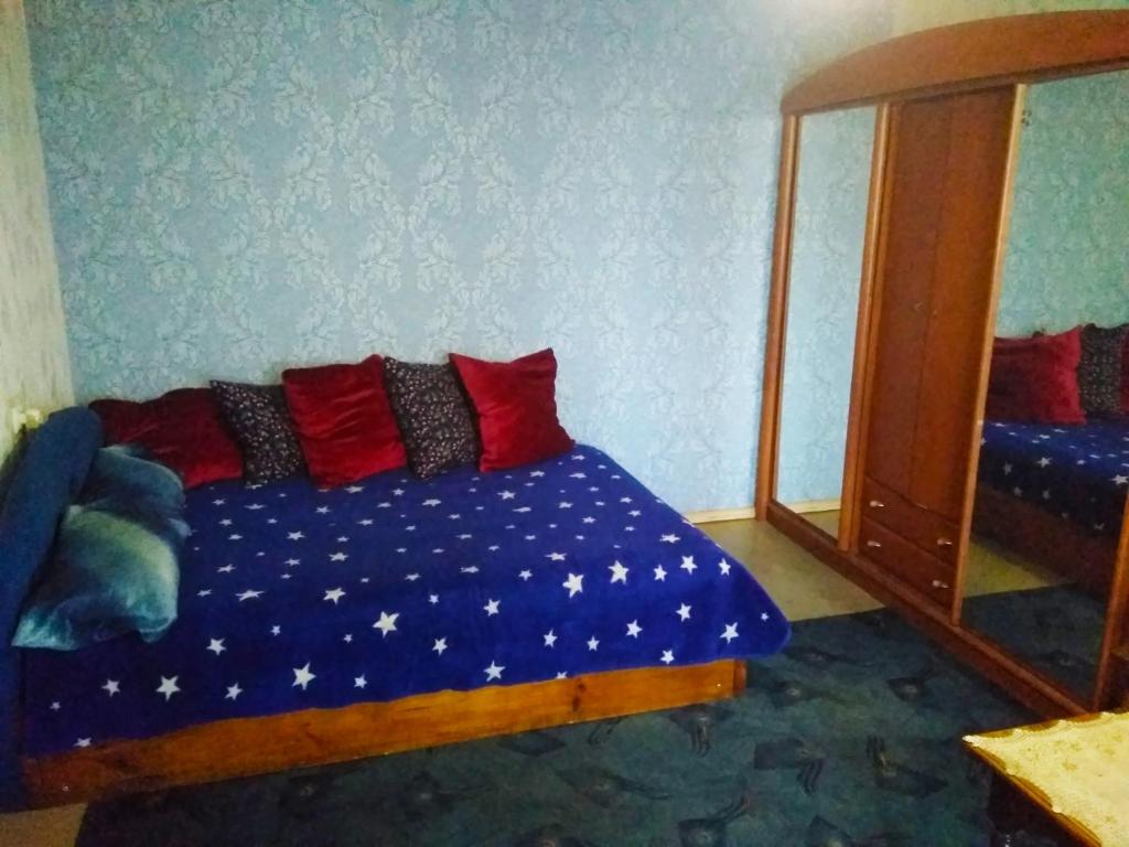 a bedroom with a bed with red pillows and a mirror at Квартира на Ленина in Okhtyrka
