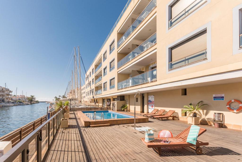 a building with a swimming pool next to the water at Pierre & Vacances Empuriabrava Marina in Empuriabrava