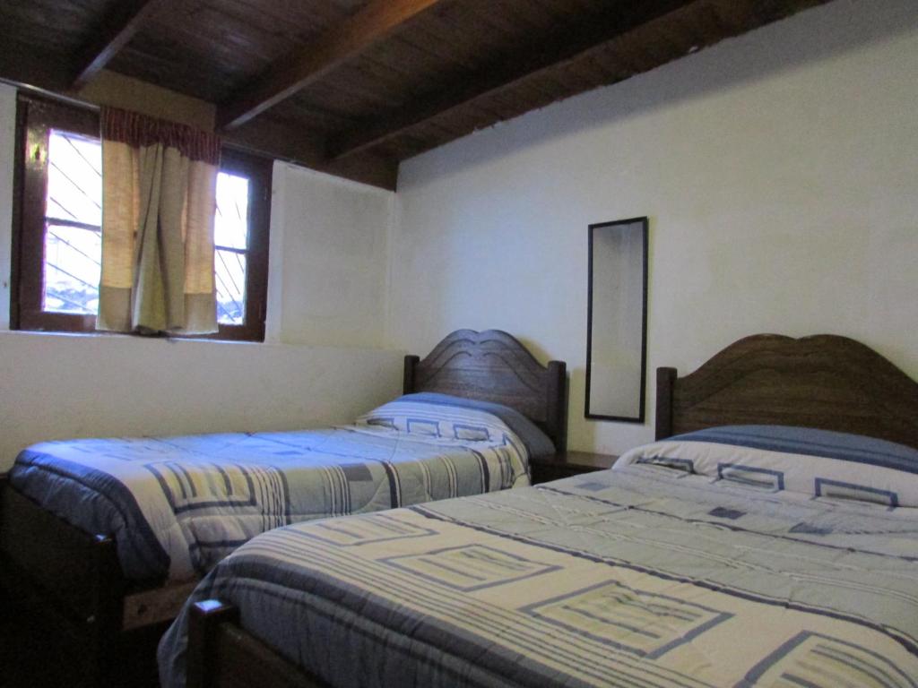 two beds in a room with two windows at Hostería Baños Morales in Santiago