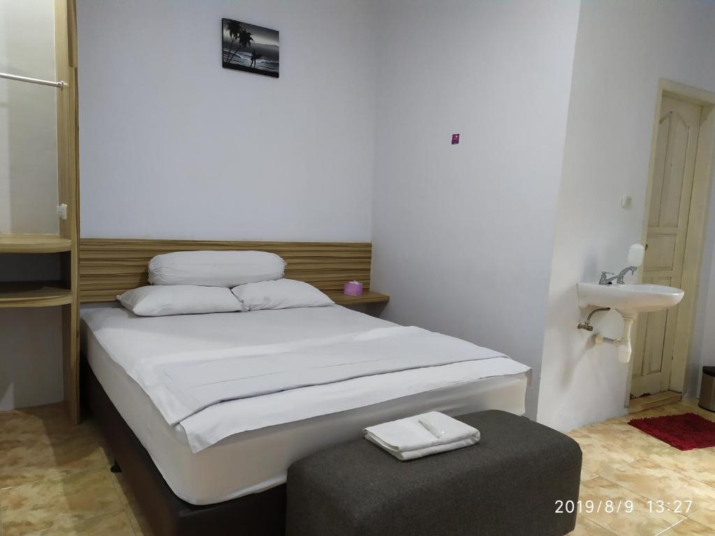 - une petite chambre avec un lit et un tabouret dans l'établissement Penginapan APEX, à Dobo