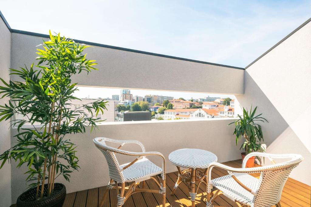 balcón con sillas, mesa y árboles en Porto Insight Apartment Cedofeita- Balcony & Parking, en Oporto