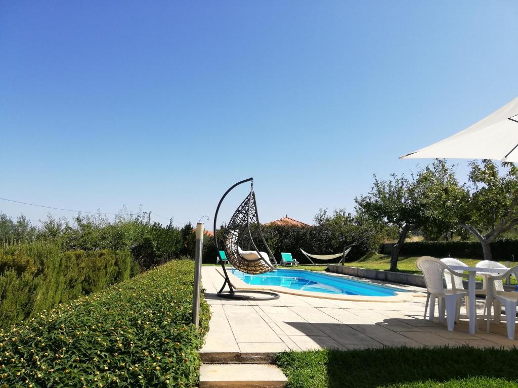 uma piscina com uma cadeira e um guarda-sol e uma mesa e cadeiras em Quinta do Retiro em Felgar