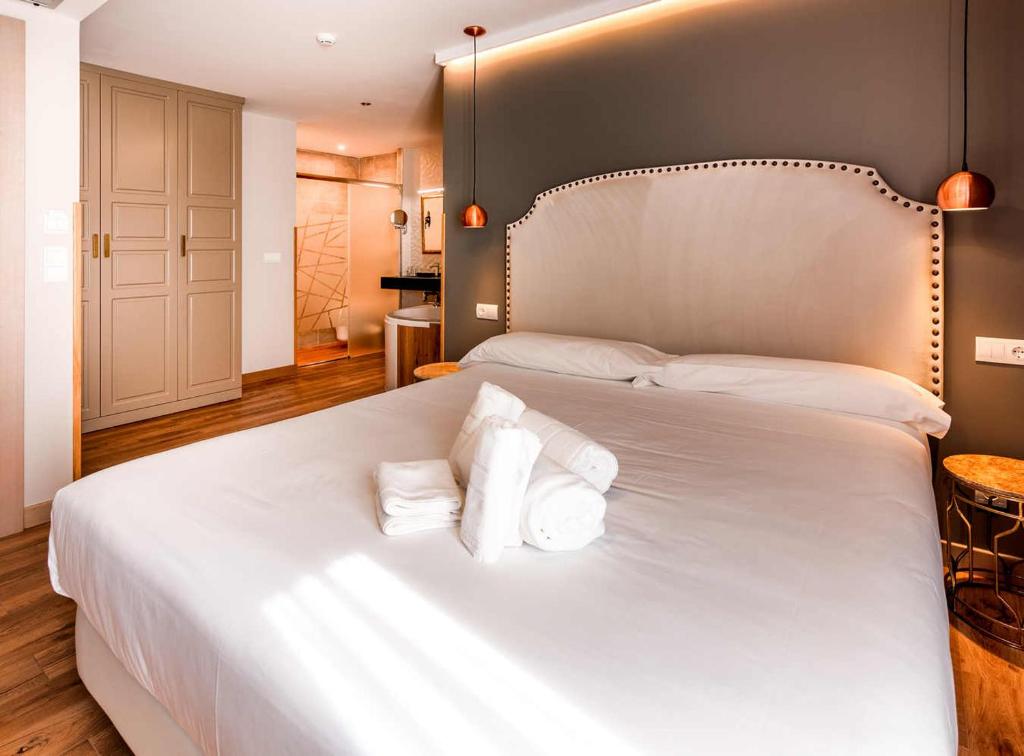 a bedroom with a large white bed with three pillows at Hotel Gastronómico Torre de Galizano in Galizano