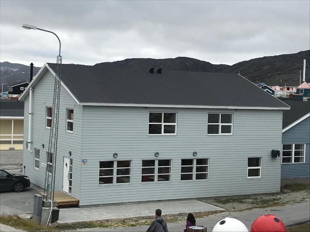 a white house with people standing in front of it at Hotel Nuka in Ilulissat